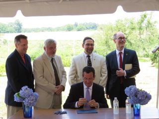 l. to r. Signing: State Senator Rob Kane, Dept. of Developmental Services Cmr. Terrance Macy, DoAg Cmr. Steve Reviczky, State Rep. Arthur O’Neill, Governor Malloy (seated). © Karen Huber