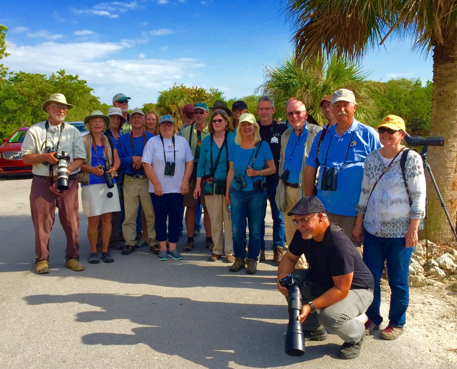 A group of Florida birders and others gathered for a quick pose to celebrate seeing the Great White Pelican, (probable female in breeding plumage), extralimital, roosting with American Pelicans, Ding Darling NWR, Sanibel Island, Florida. ©Mardi Welch Dickinson/ KymryGroup™ All Rights Reserved. Photo may not be used without written permission.